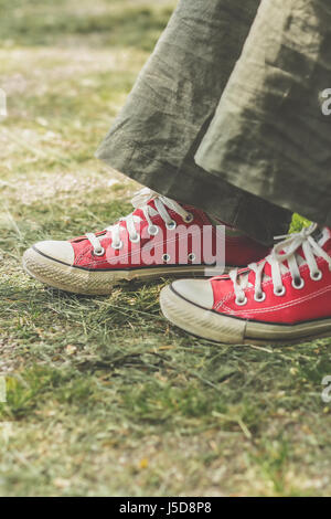 Les pieds dans les chaussures de toile rouge sur l'herbe Banque D'Images