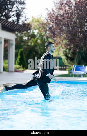 L'homme d'apprécier un moment de détente dans la piscine avec le costume. Banque D'Images