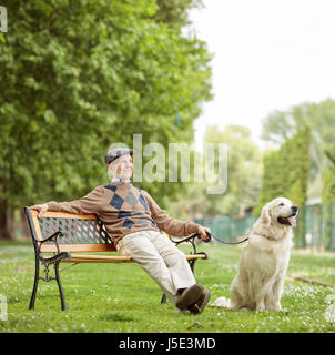 Un homme âgé avec un chien assis sur un banc en bois dans le parc Banque D'Images