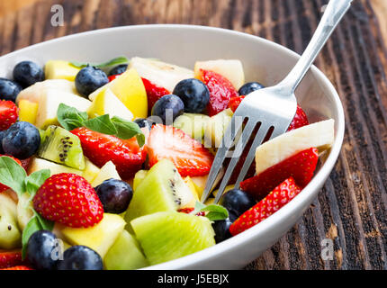 Bol de salade de fruits avec les fraises, les bleuets, les pommes, les kiwis, les bananes en tranches, salade de fruits d'été saison saine assortiment Banque D'Images