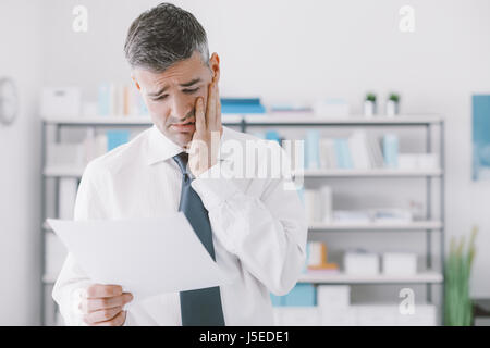 Desperate businessman dans le bureau qui reçoit les factures trop chères, d'affaires et coûts concept Banque D'Images