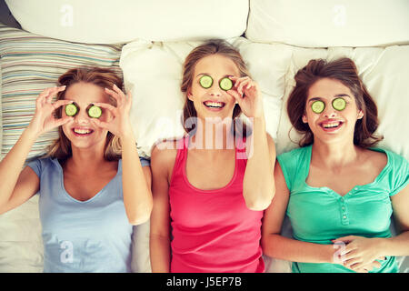 Heureux les jeunes femmes avec masque de concombre au lit Banque D'Images