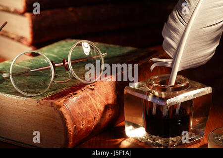 Vintage still life. Vieux livre sur les lunettes en verre près de l'encrier avec plume Banque D'Images