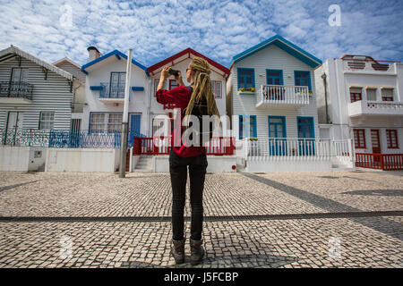 Traveller girl dreadlocks est prend photo sur un smartphone maisons à rayures en Costa Nova, Portugal Banque D'Images