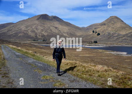 Femme seule Hillwalker marche sur la vieille route d'Tomdoun près de Loch Cluanie Glen Shiel, Kintail, N/W Scottish Highlands, Ecosse Banque D'Images