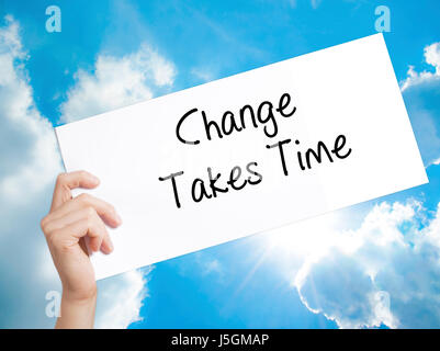 Le changement nécessite du temps signer sur papier blanc. Tenir la main de l'homme papier avec texte. Isolé sur fond de ciel. Concept d'entreprise. Stock Photo Banque D'Images