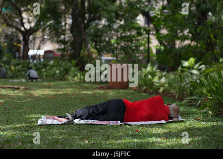 Un homme de prendre une sieste dans un parc à Mumbai, Inde. Banque D'Images