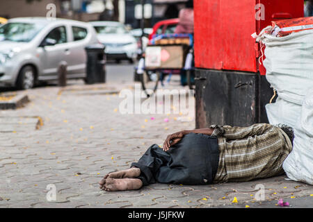 Un sans-abri dormant dans un coin de rue à Mumbai, Inde. Banque D'Images