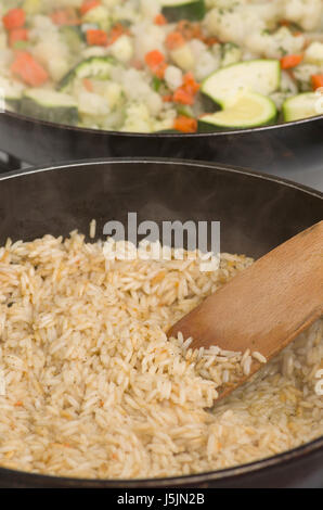 Cuire le dîner. Dans la poêle, faire cuire le risotto, et de l'autre faites revenir les légumes. Banque D'Images