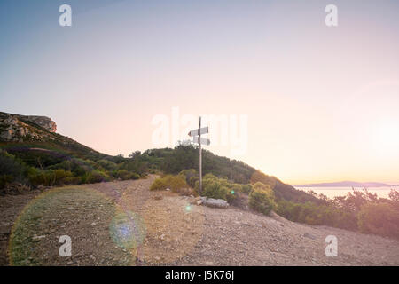 Paysage rural avec carrefour sur la colline dans la forêt au coucher du soleil. Deux directions différentes. Concept de choisir la bonne voie. Chemin de gauche et droite. Banque D'Images