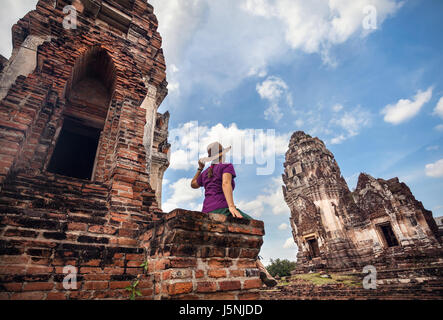 Woman in hat looking at ancient Temple en ruines de la ville de Lopburi, Thaïlande Banque D'Images