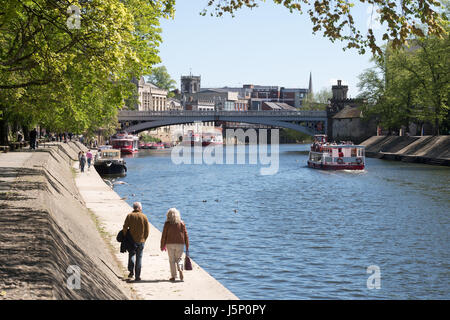 Un couple en train de marcher le long de la rivière vers Lendal Bridge, York, North Yorkshire, Angleterre, Royaume-Uni Banque D'Images