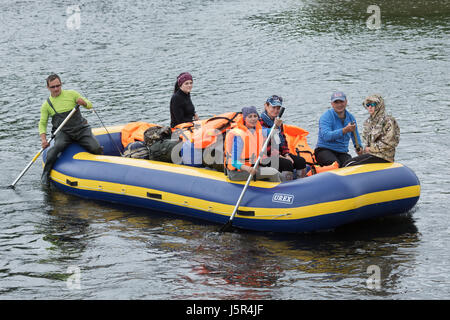 Rafting été sur la péninsule du Kamtchatka en bateau rafting : météo sombres avec des voyageurs à bord flotte sur les vagues sur la rivière de montagne boueux. Banque D'Images