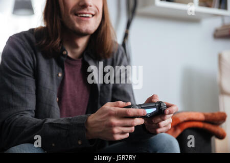 Portrait of happy young man gamer assis à la maison à l'intérieur et jouer des jeux avec joystick. Banque D'Images