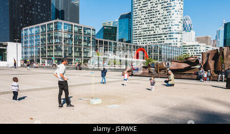 Nanterre, France - 09 mai 2017 : un homme, vu par des passants, fait des bulles géantes au milieu de la place centrale de la défense, le grand Banque D'Images