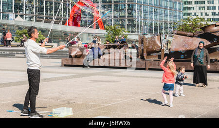Nanterre, France - 09 mai 2017 : un homme, vu par des passants, fait des bulles géantes au milieu de la place centrale de la défense, le grand Banque D'Images