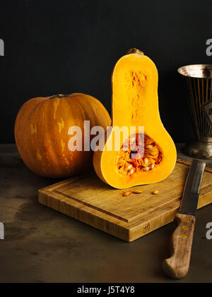 La muscade et la citrouille citrouille butternut halfed sur une planche à découper en bois Banque D'Images