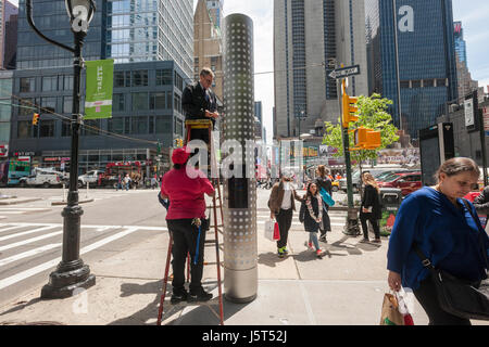 Les travailleurs à s'adapter l'une des nouvelles bornes d'orientation qui se tiennent à chaque extrémité du Restaurant Row, à New York, West 46th Street entre 8th et 9th Avenues, le mardi 16 mai 2017. Au moins quatre ans les kiosques lumineux indiquent les noms des nombreux restaurants qui peuplent la rue. Le dévoilement est juste à temps pour le goût de Times Square événement se déroulant dans la rue le 5 juin. (© Richard B. Levine) Banque D'Images