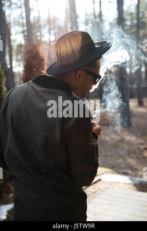 Vue arrière photo de african man standing en plein air dans la forêt de fumer. Banque D'Images
