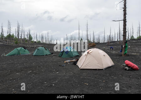 Tentes tourisme comité permanent dans le bois mort sur les scories, cendres volcaniques Éruptions volcaniques du volcan Tolbachik - conséquence de l'éruption catastrophique sur la péninsule du Kamtchatka. Banque D'Images