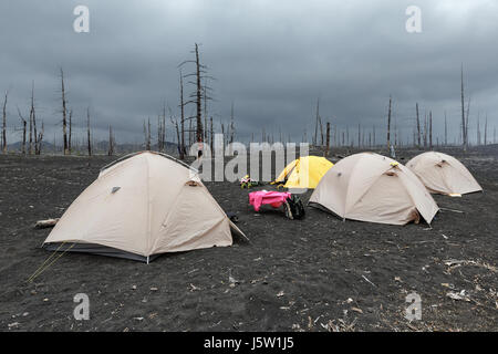 Tentes tourisme dans le bois mort sur les scories volcaniques et de cendres volcaniques du volcan Tolbachik - conséquence de l'éruption catastrophique sur la péninsule du Kamtchatka. Banque D'Images