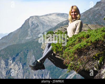 La fille est assise sur le bord de la falaise, le Geirangerfjord Banque D'Images