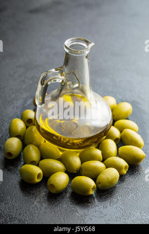 L'huile d'olive et olives sur noir table de cuisine. Banque D'Images