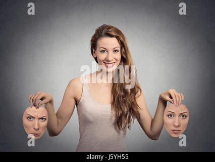 Magnifique portrait happy girl détient deux masques gris isolé wall background. Visage humain expressions, émotions, sentiments, état d'esprit concept bipolaire Banque D'Images