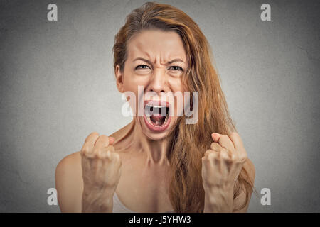 Closeup portrait jeune femme en colère atomique nerveux ayant hystérique, hurlant, poings ventilation jusqu'à l'air gris fond Mur isolé. Huma négatif Banque D'Images