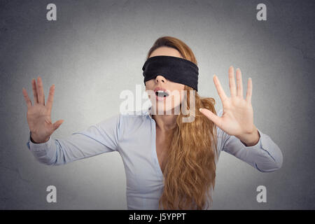 Young businesswoman walking bandé les yeux avec les mains en avant isolé sur fond de mur gris Banque D'Images