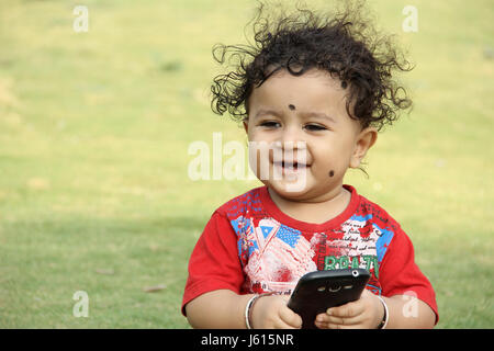 Petit enfant avec le mobile dans la main à la recherche and smiling Banque D'Images