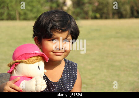 Petite fille indienne avec sa poupée dans le jardin Banque D'Images