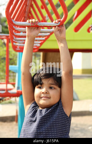 Petite fille jouant avec monkey bars in garden Banque D'Images