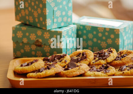 De délicieux biscuits fraîchement cuits au four avec du chocolat sur un plateau en bois avec un arrière-plan flou Banque D'Images