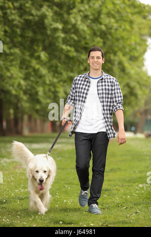 Portrait d'un jeune homme avec un chien à marcher en direction de la caméra dans un parc Banque D'Images