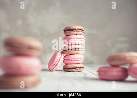 Framboise et chocolat Macarons de couleur pastel ou macarons sur fond noir en béton Banque D'Images