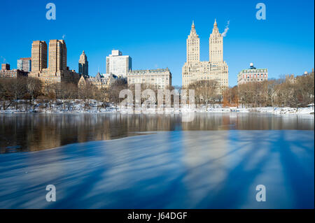 Vue panoramique de l'Upper West Side skyline se reflétant dans la glace du lac de Central Park le matin après une tempête de neige Banque D'Images