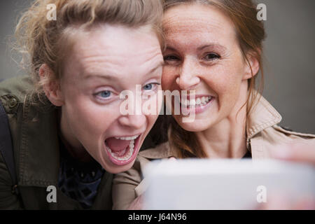 Espiègle, laughing women friends with camera phone selfies Banque D'Images