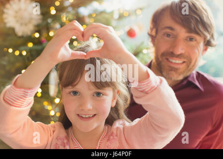 Portrait smiling father and daughter formant coeur-shape near Christmas Tree Banque D'Images