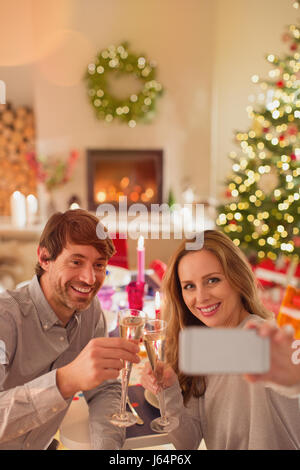 Smiling couple drinking champagne et en tenant à selfies table de dîner de Noël Banque D'Images