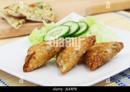 Apéritif composé de samosas Indiens avec salade verte sur plaque blanche sur la surface en bois Banque D'Images