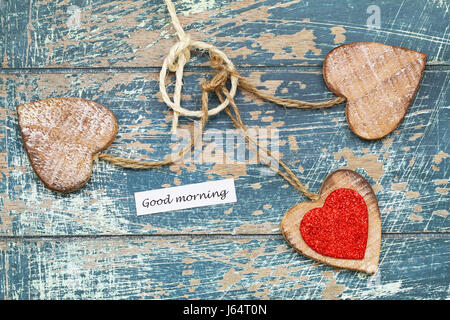 Bonjour carte avec trois coeurs en bois sur la surface en bois rustique Banque D'Images