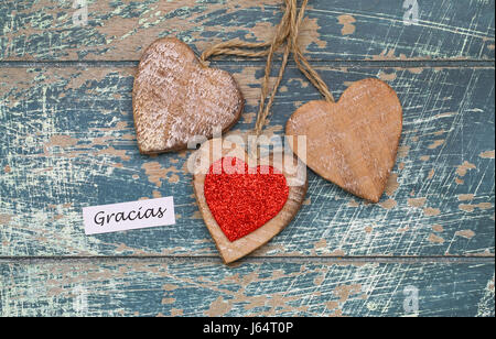 Gracias (merci en espagnol) Carte avec trois coeurs en bois sur la surface en bois rustique Banque D'Images