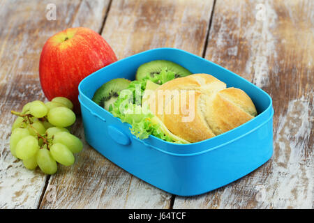 School lunch box sandwich au fromage contenant des fruits : kiwi, pomme et raisin sur la surface en bois rustique Banque D'Images