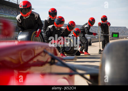 Pit Crew avec pneus presque prêt pour voiture de course de Formule Un dans le pit lane Banque D'Images