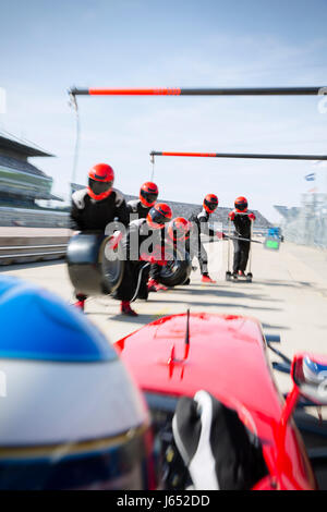 Pit Crew avec pneus presque prêt pour voiture de course de Formule Un dans le pit lane Banque D'Images