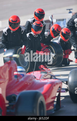 Pit Crew avec pneus presque prêt pour voiture de course de Formule Un dans le pit lane Banque D'Images