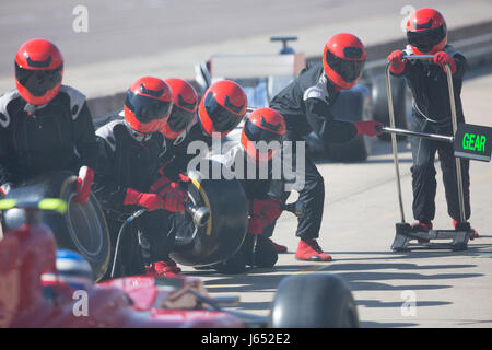 Pit Crew avec pneus presque prêt pour voiture de course de Formule Un dans le pit lane Banque D'Images