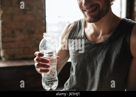 Portrait of a smiling man holding fitness sain bouteille d'eau à la salle de sport Banque D'Images