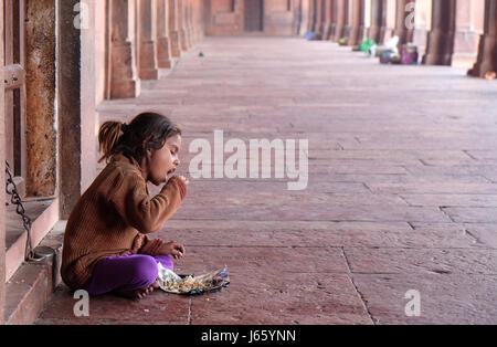 Une pauvre fille manger en Fatehpur Sikri complexe, Uttar Pradesh, Inde, 15 février 2016. Banque D'Images